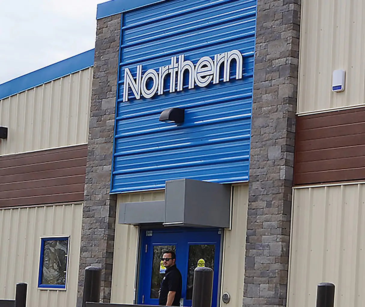 Door and signage of Northern Store with a man in a black shirt standing in front