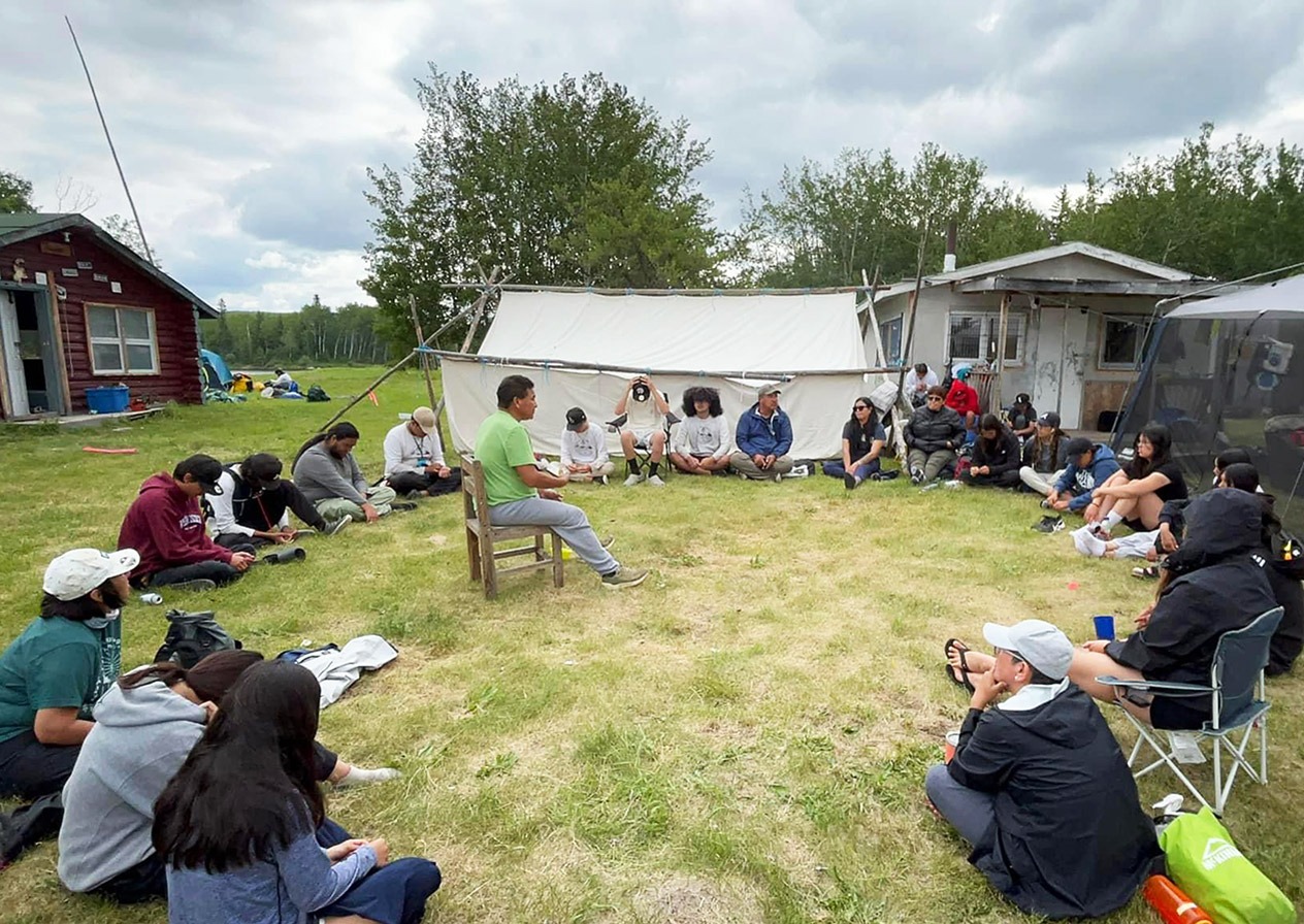 students sitting in a circle listening to a leader"