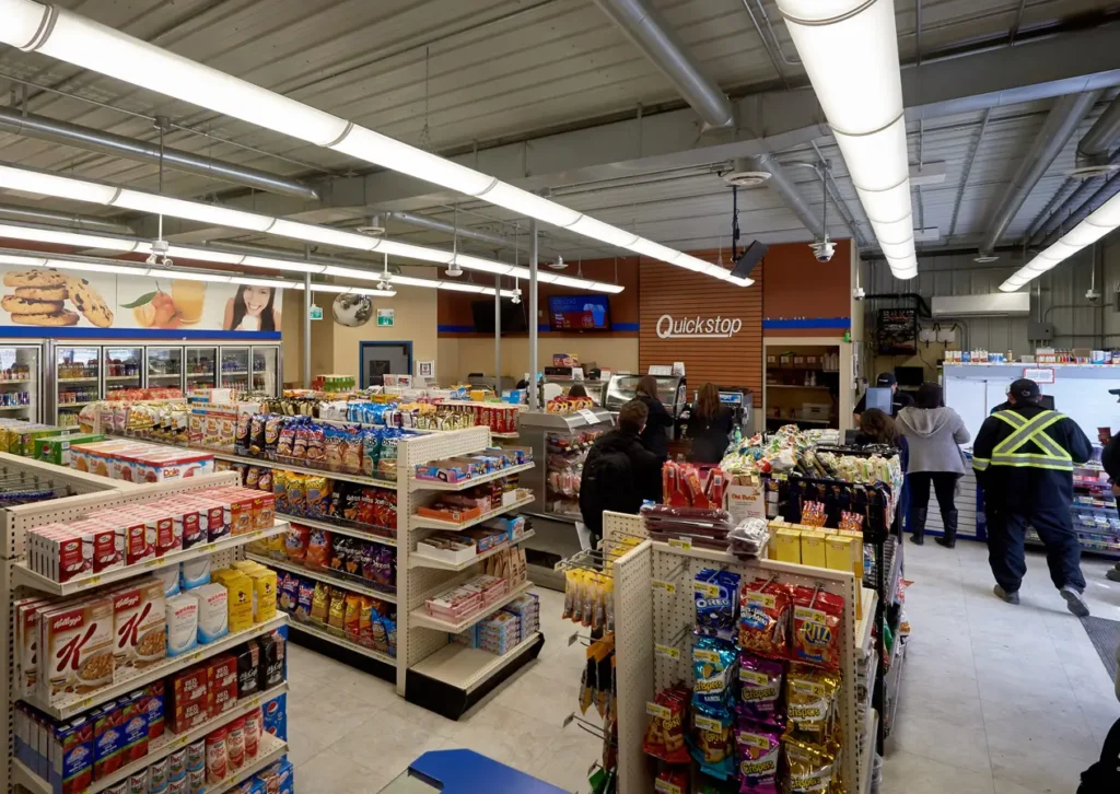 QuickStop store with aisles of cereal and chips. People standing in line.