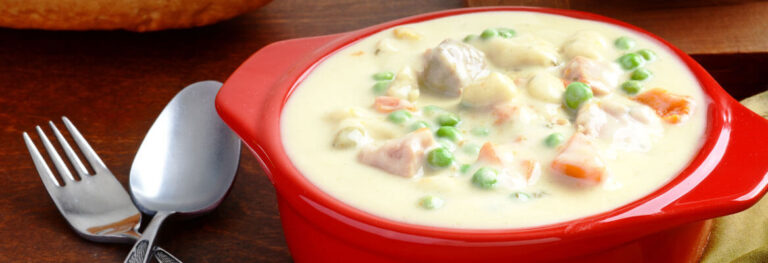 Creamy Chicken Potato Soup in a red bowl with a fork and spoon beside it