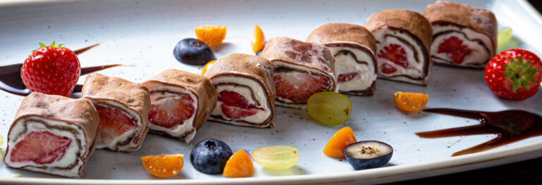 white plate with fruit cheesecake sushi