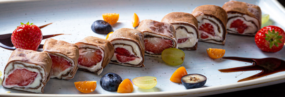 white plate with fruit cheesecake sushi