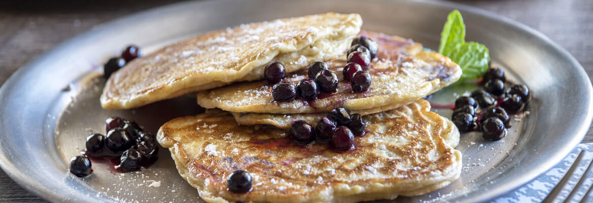 plate full of pancakes with blueberries scattered